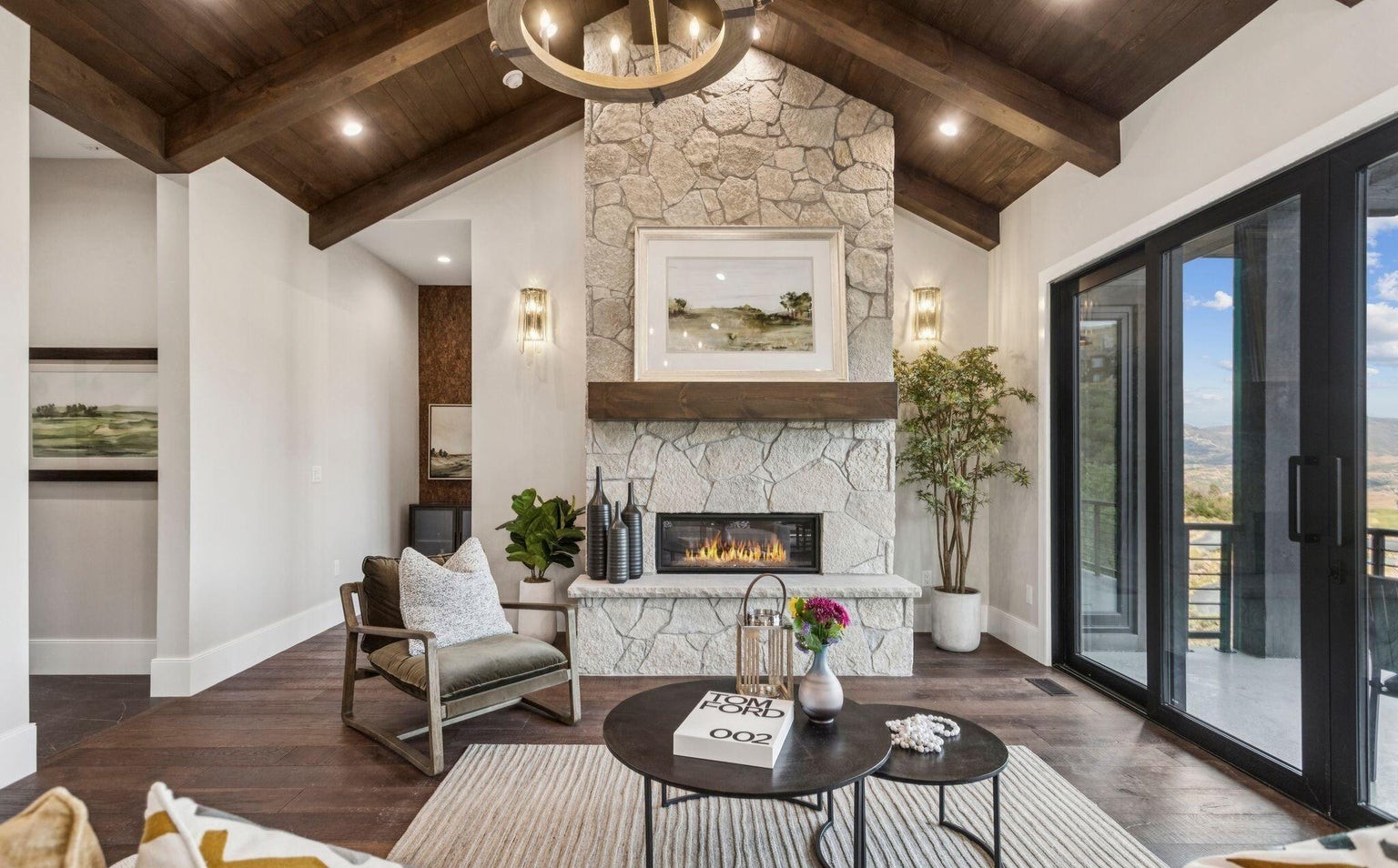 Upper living area with vaulted stone fireplace, wood beams, and sliding doors to deck