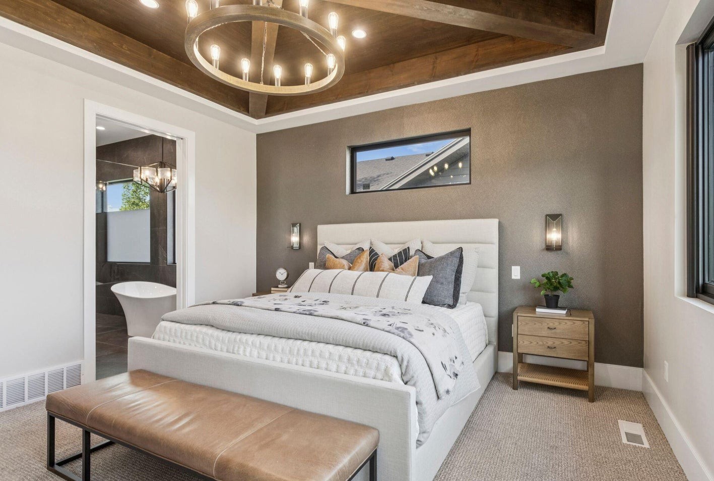 Master bedroom with wood beam tray ceiling, chandelier, and en-suite bath visible