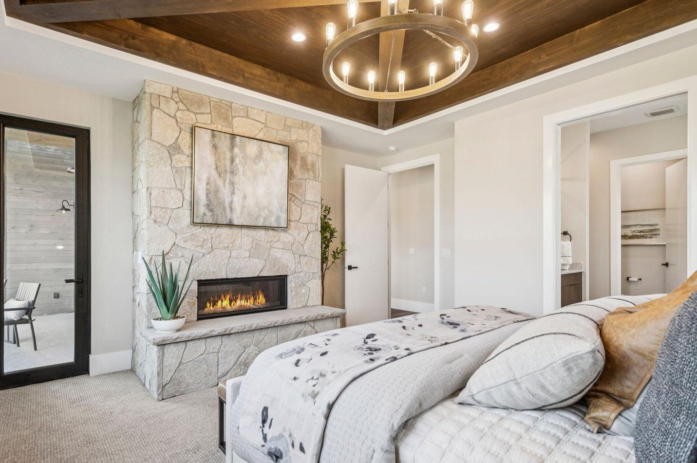 Master bedroom stone fireplace with linear gas insert and beam ceiling
