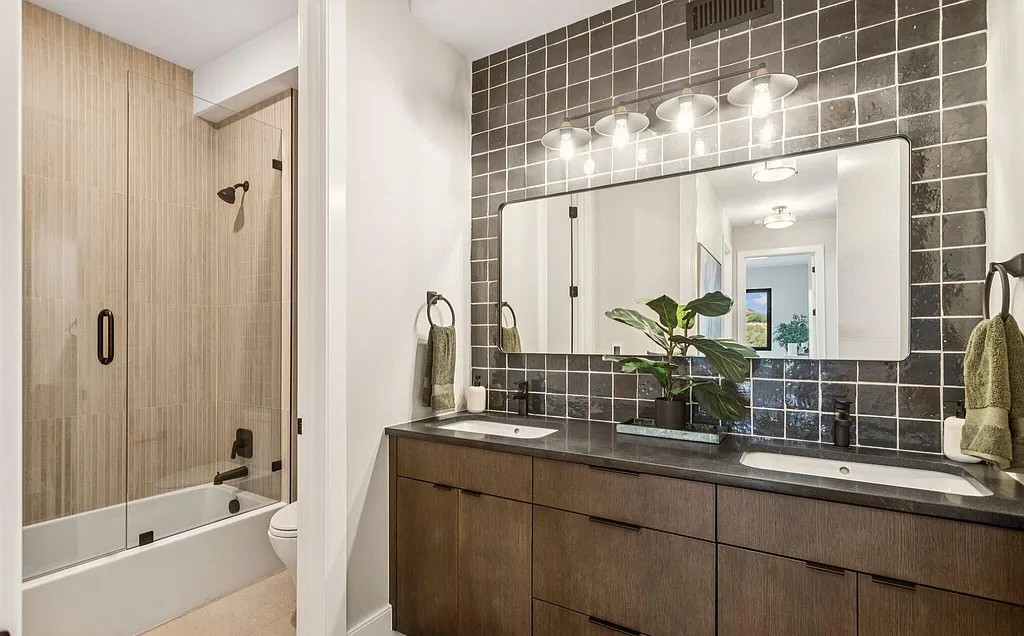 Guest bathroom with dark tile and dual vanity