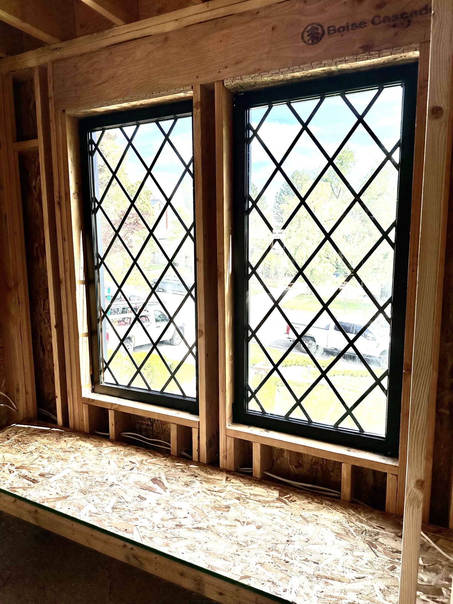 Close-up of diamond-pane window installation detail — precision shimming visible, new framing meets old structure