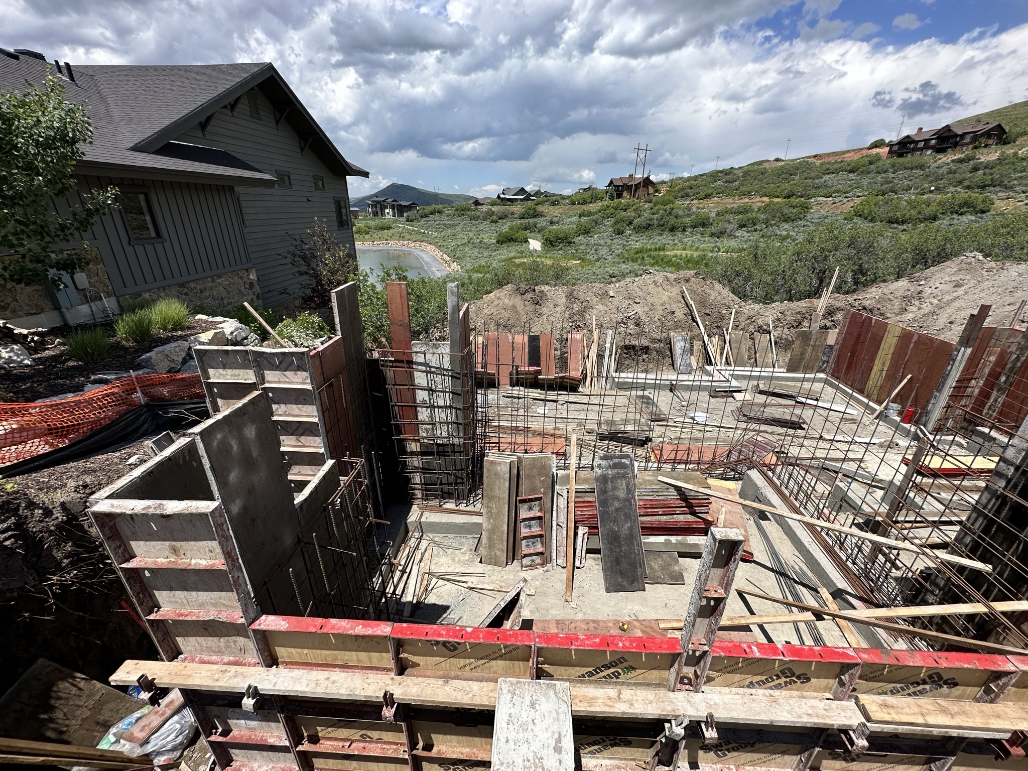 Foundation forms and rebar with neighboring home providing scale context