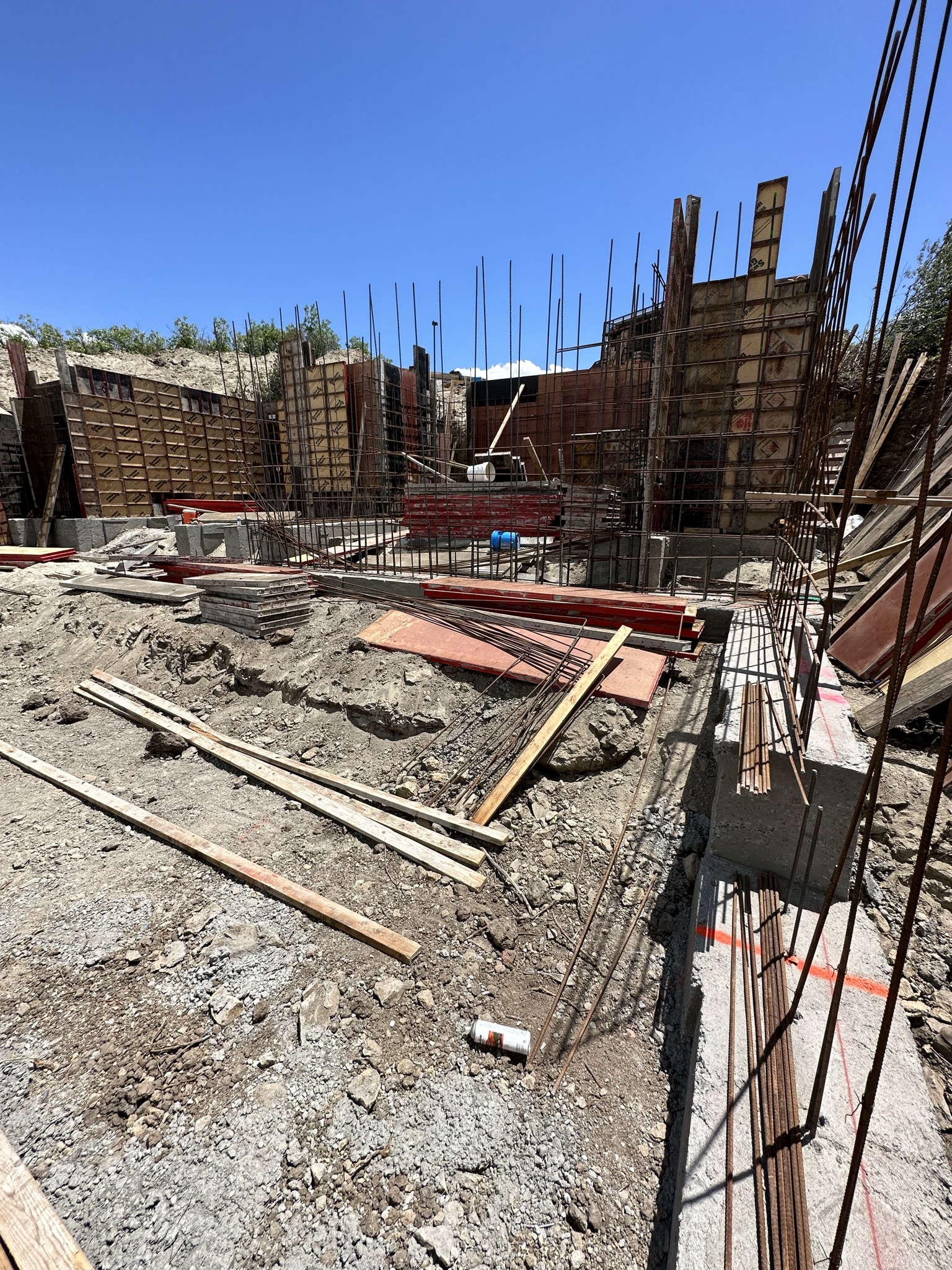 Dramatic ground-level view of rebar verticals and foundation forms against clear blue sky