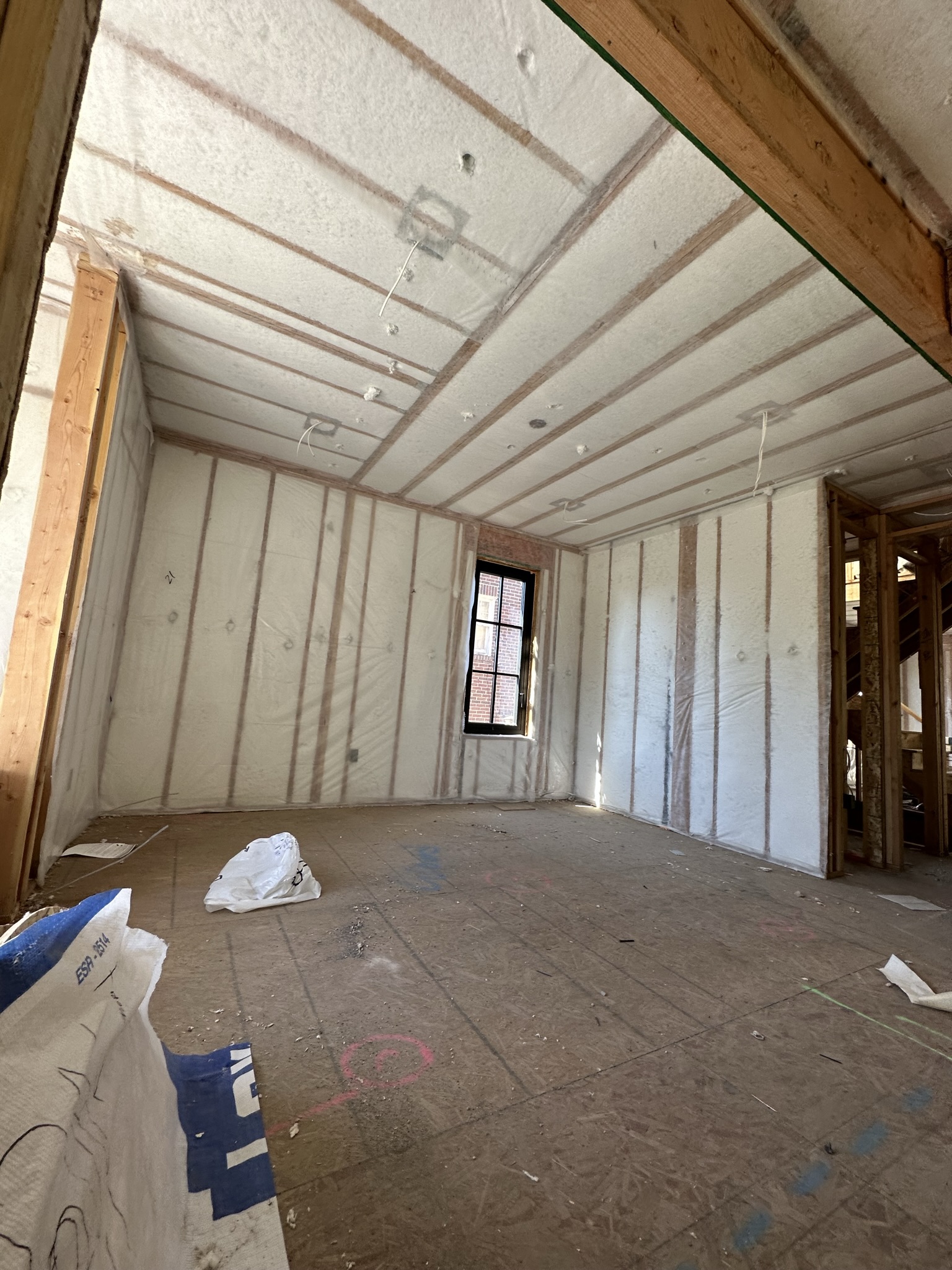 Closed-cell spray foam insulation covering walls and vaulted ceiling — complete thermal envelope in the new addition, high-performance building science