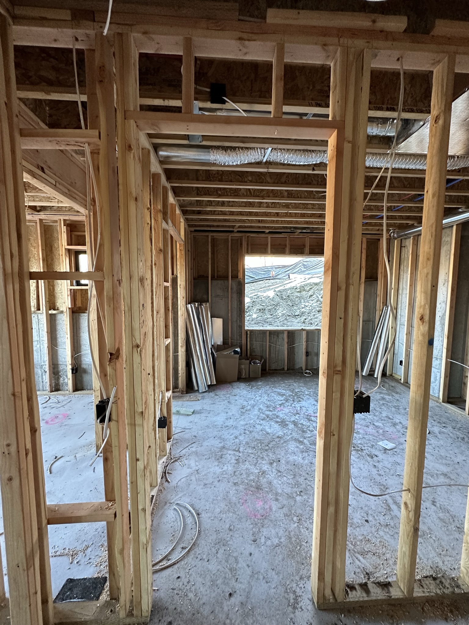 Interior framing — looking through stud walls and doorways, HVAC ductwork visible in ceiling, wiring started