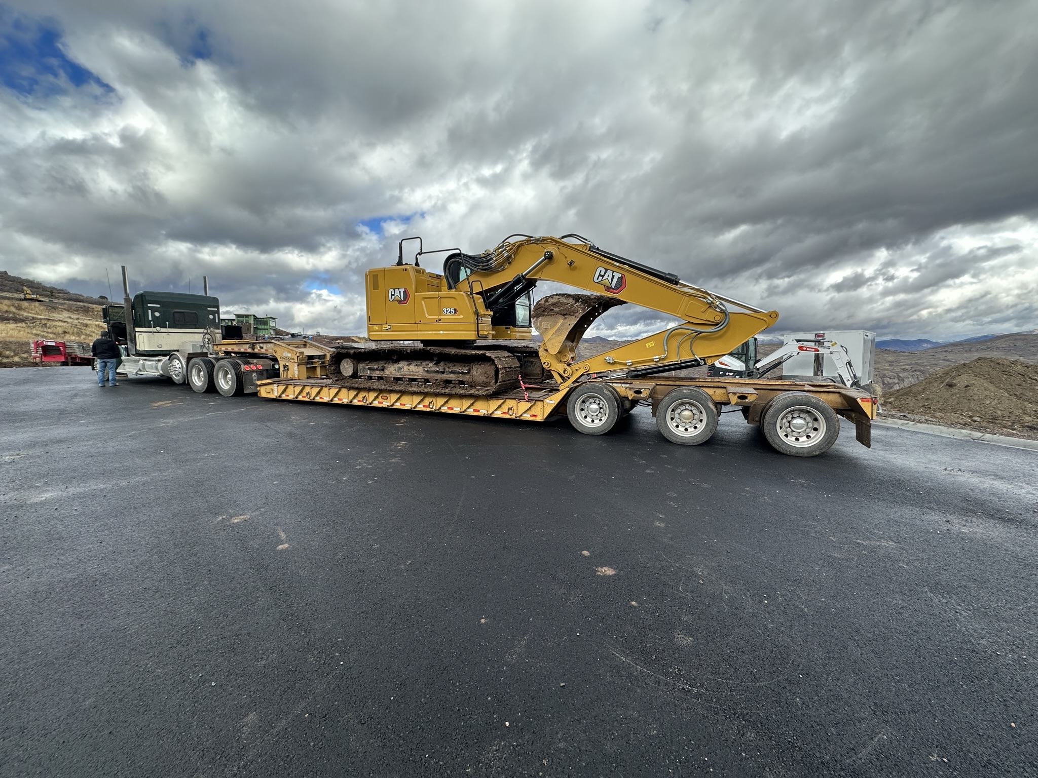 Heavy equipment arriving on flatbed trailer — Day One on the Hideout job site