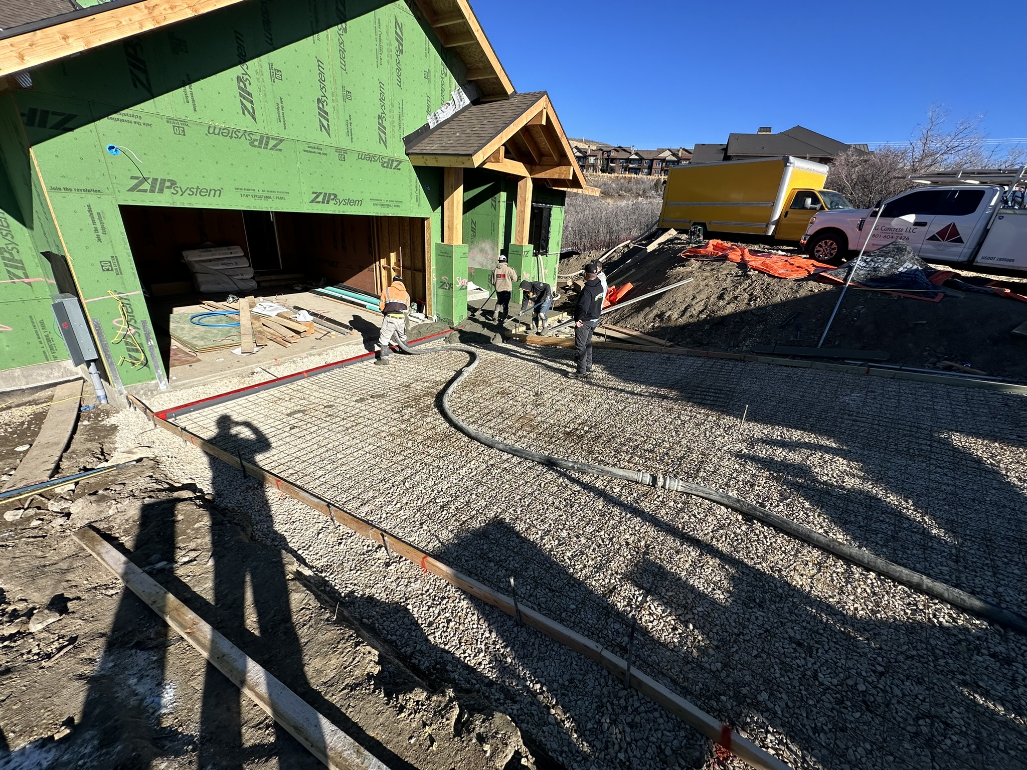 Concrete being poured for the driveway and garage pad with ZIP system garage framing visible