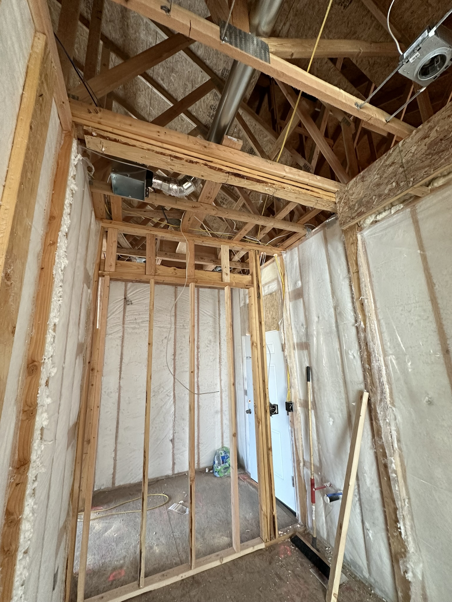 Interior framing with spray foam insulation applied to walls and ceiling, HVAC ductwork and electrical rough-in visible