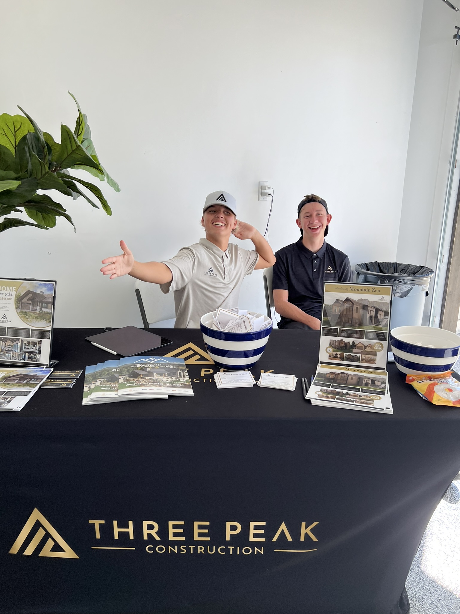 Three Peak Construction team at the 2024 Parade of Homes event booth with branded materials and marketing collateral