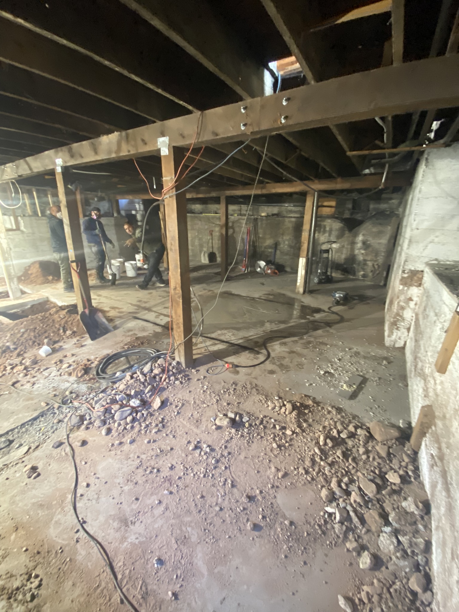 New steel I-beam installed across basement ceiling, supported by engineered columns on new footings — structural upgrade from wood to steel