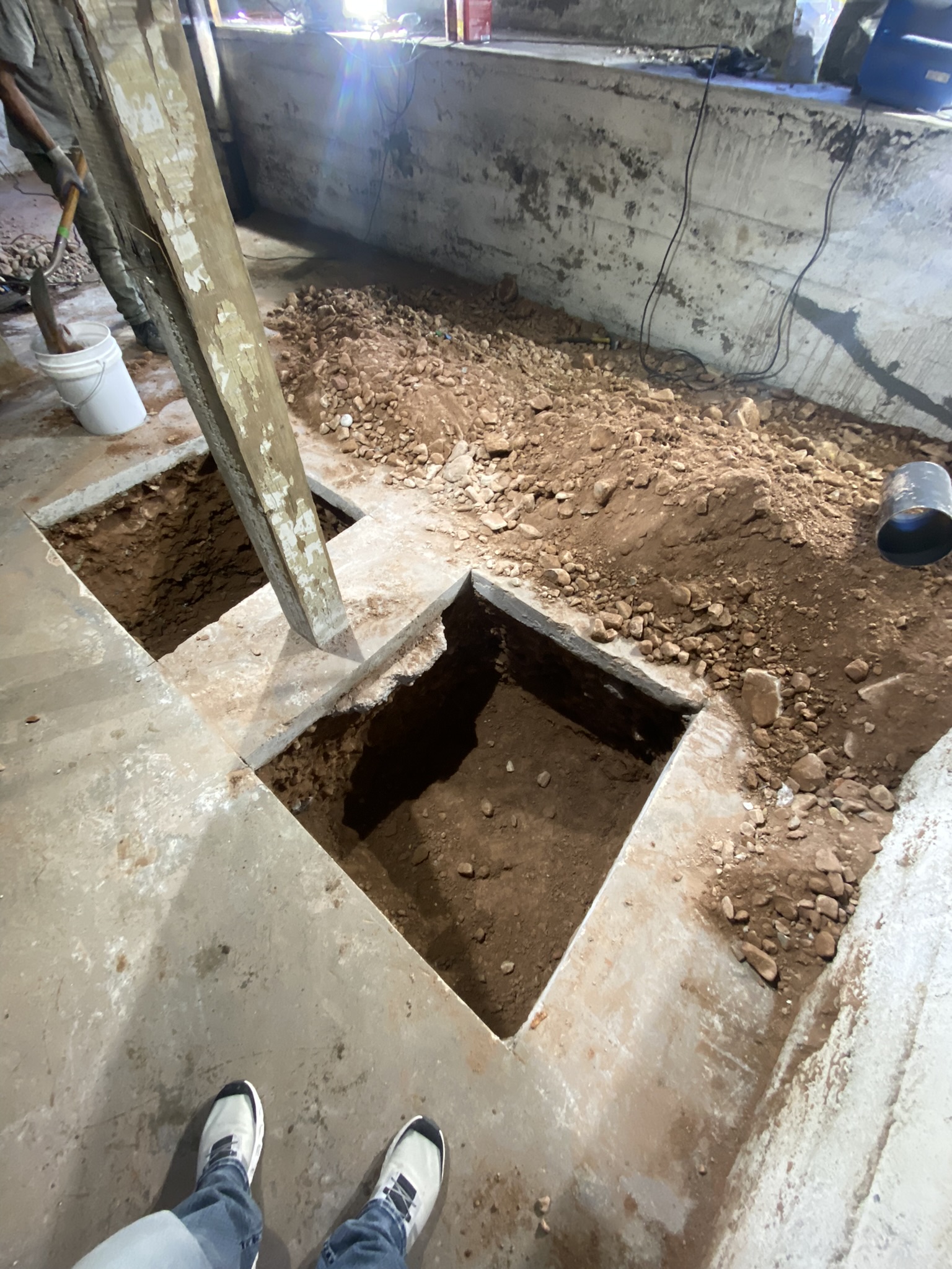 Close-up of precision footing excavation pit with clean concrete cuts and exposed soil ready for new footing pour