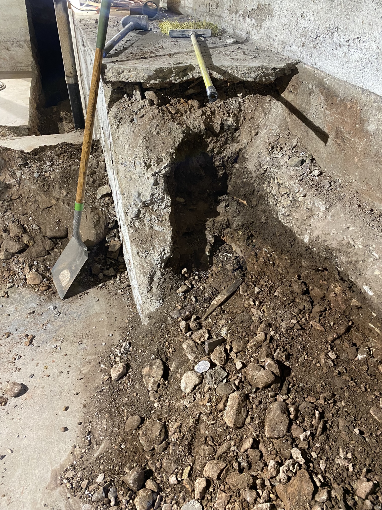 Undermined foundation footing with exposed soil beneath — structural failure in progress