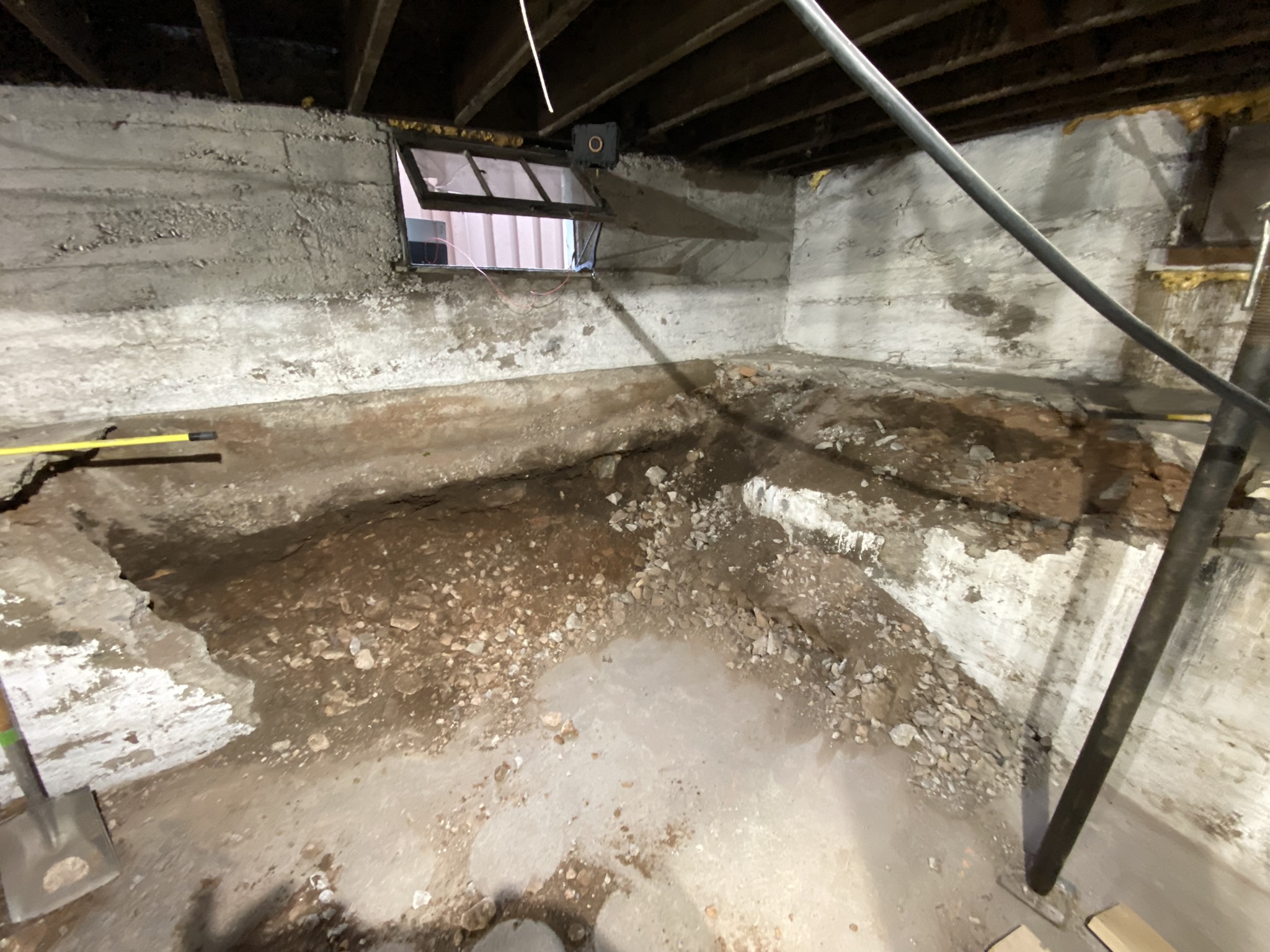 Original basement crawlspace with failing foundation — exposed dirt, temporary supports, crumbling concrete walls
