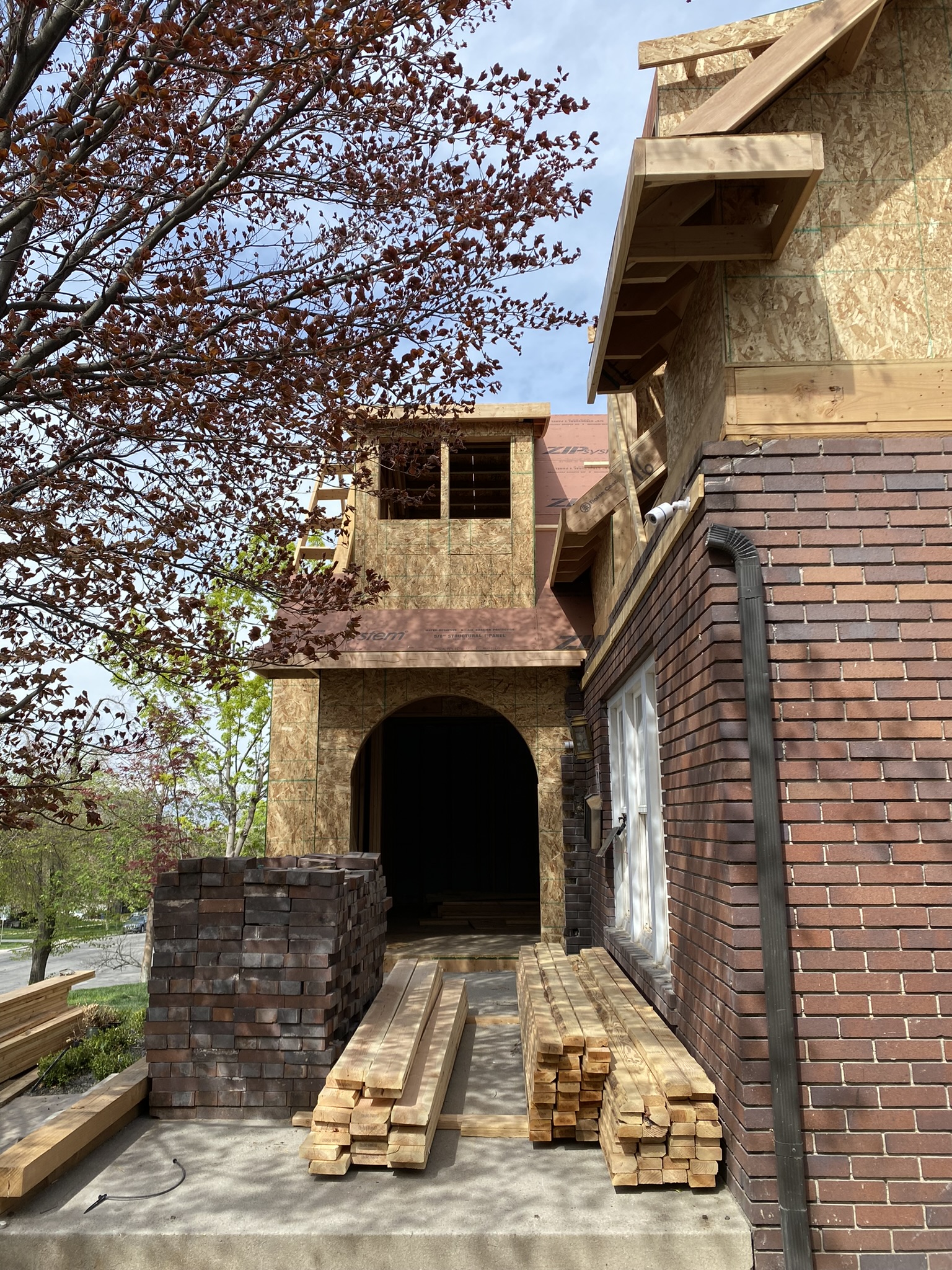 Close angle of entry addition showing ZIP System sheathing, brick stacks for matching, lumber delivery on site