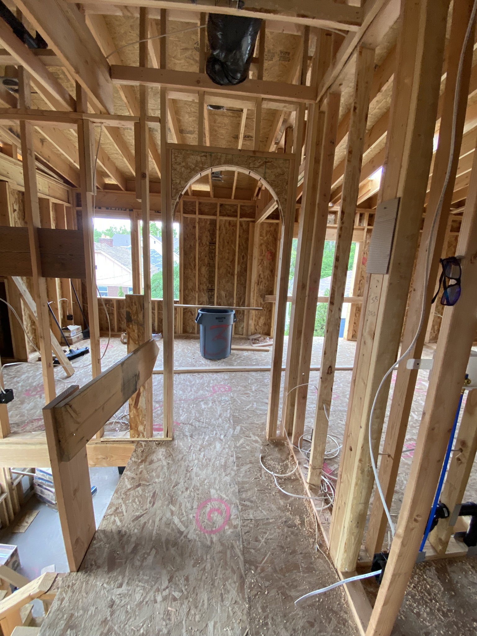 Interior framing with PEX plumbing rough-in visible — red and blue supply lines running through studs, ABS drain pipe, electrical boxes mounted