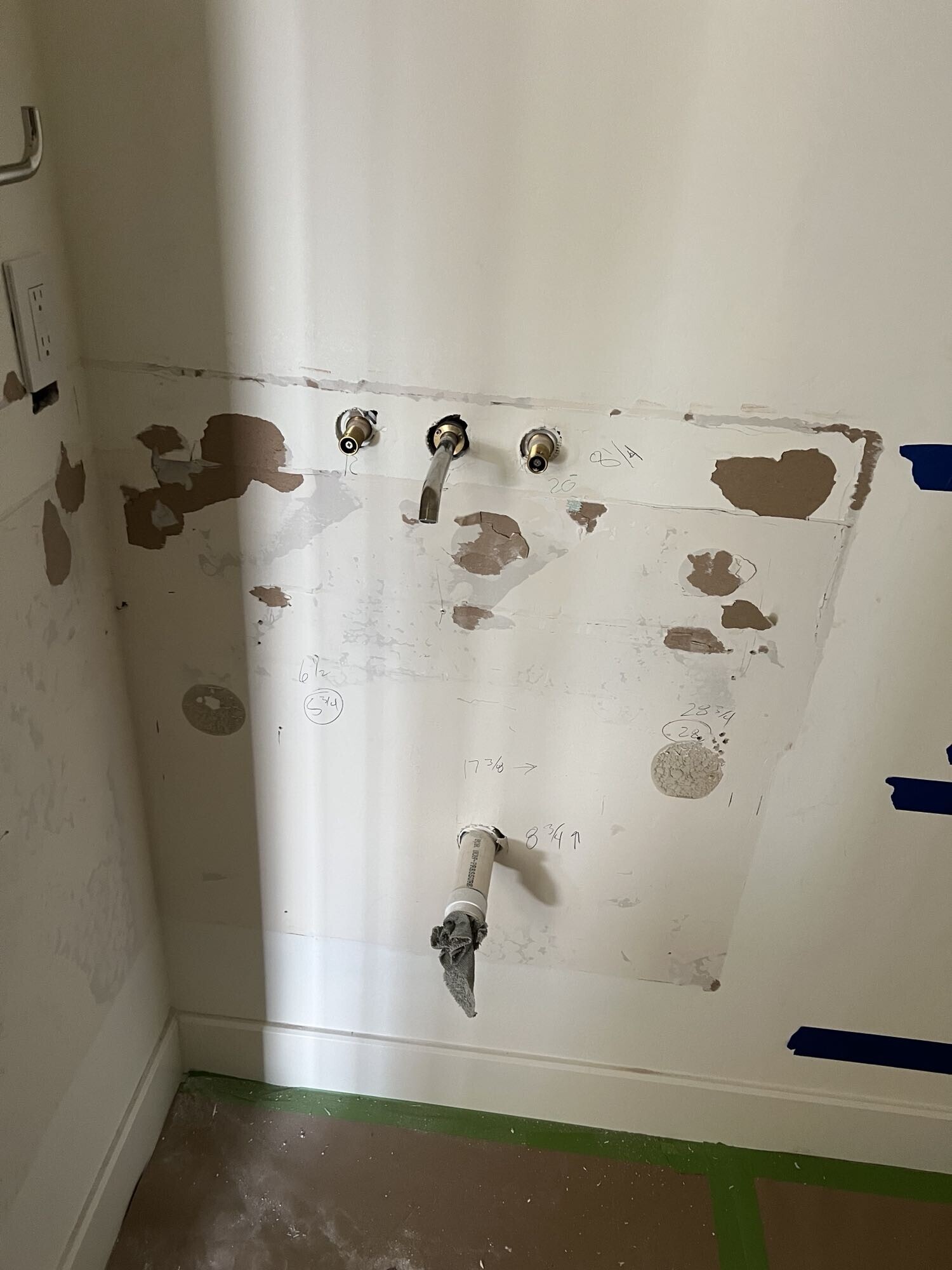 Exposed plumbing and drywall during powder room demolition — supply lines and drain visible before relocation