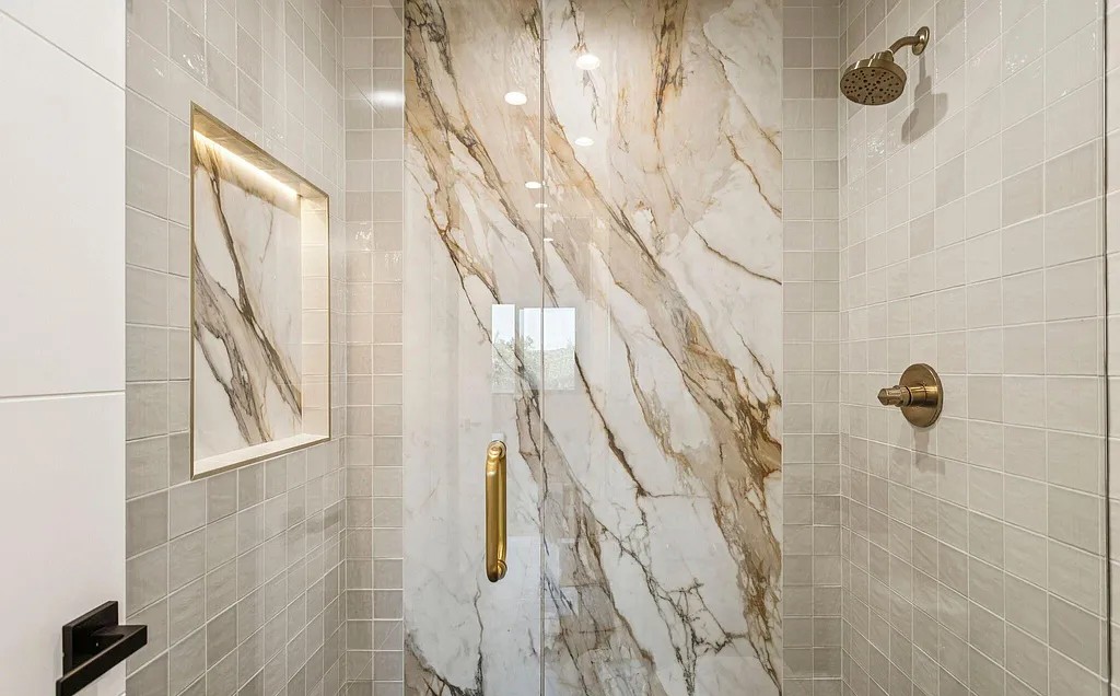 Marble shower accent slab with gold hardware and recessed niche