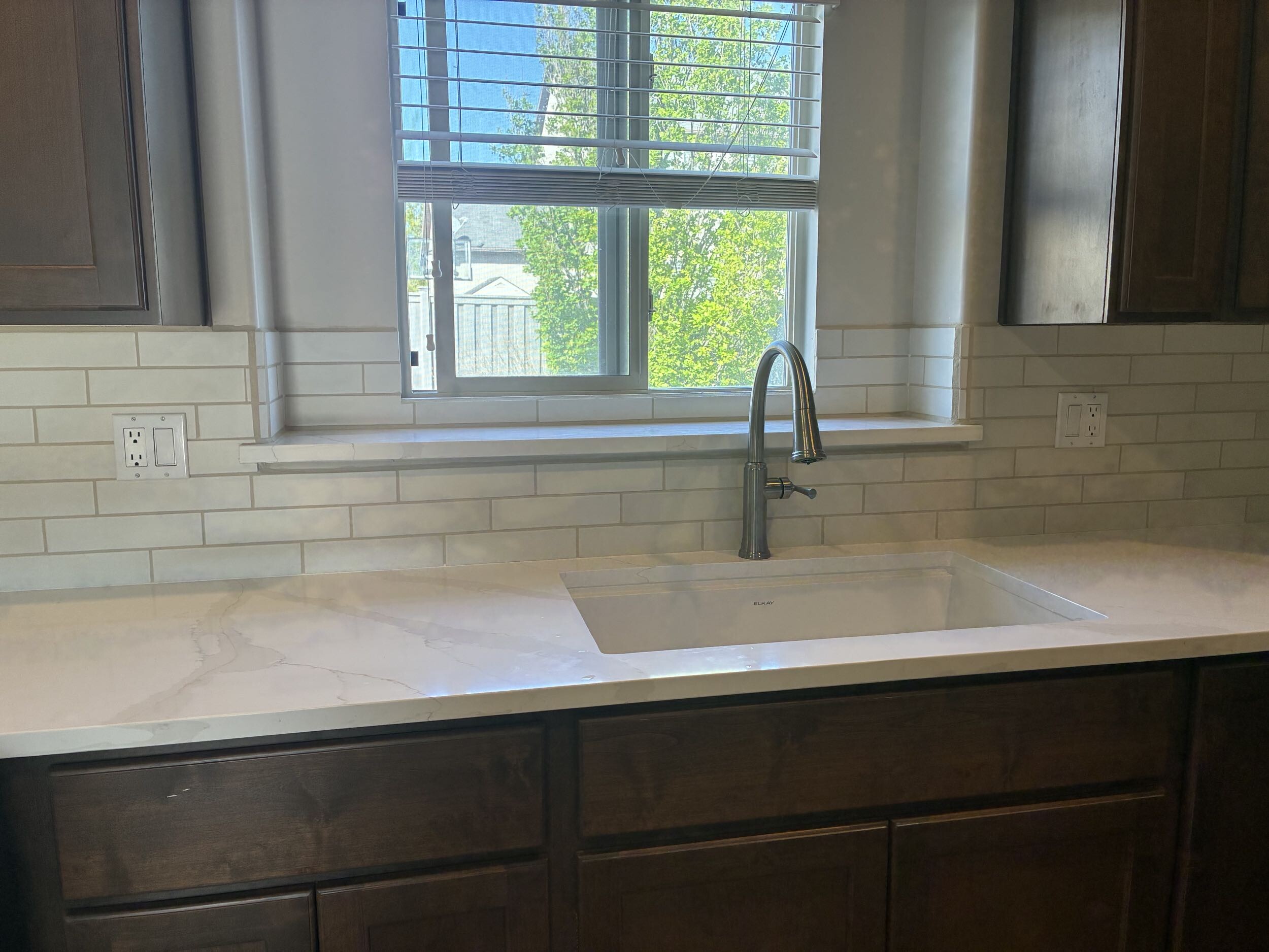 Quartz countertop with undermount sink, subway tile backsplash, and brushed nickel faucet — finished kitchen detail