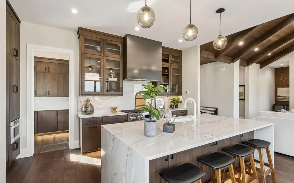 Kitchen with waterfall marble island and dark cabinetry