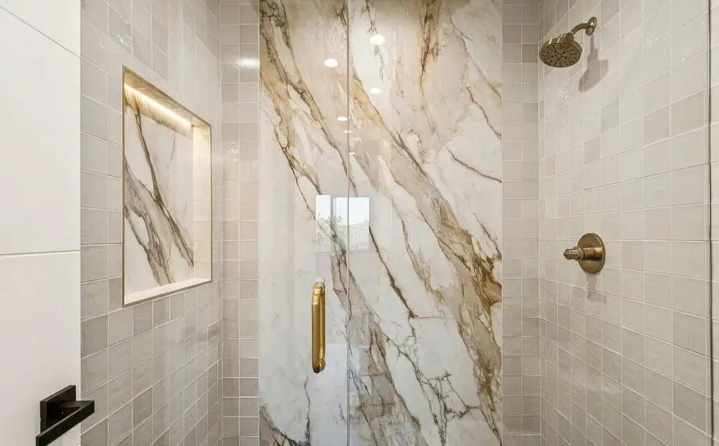 Marble shower accent slab with gold hardware and recessed niche