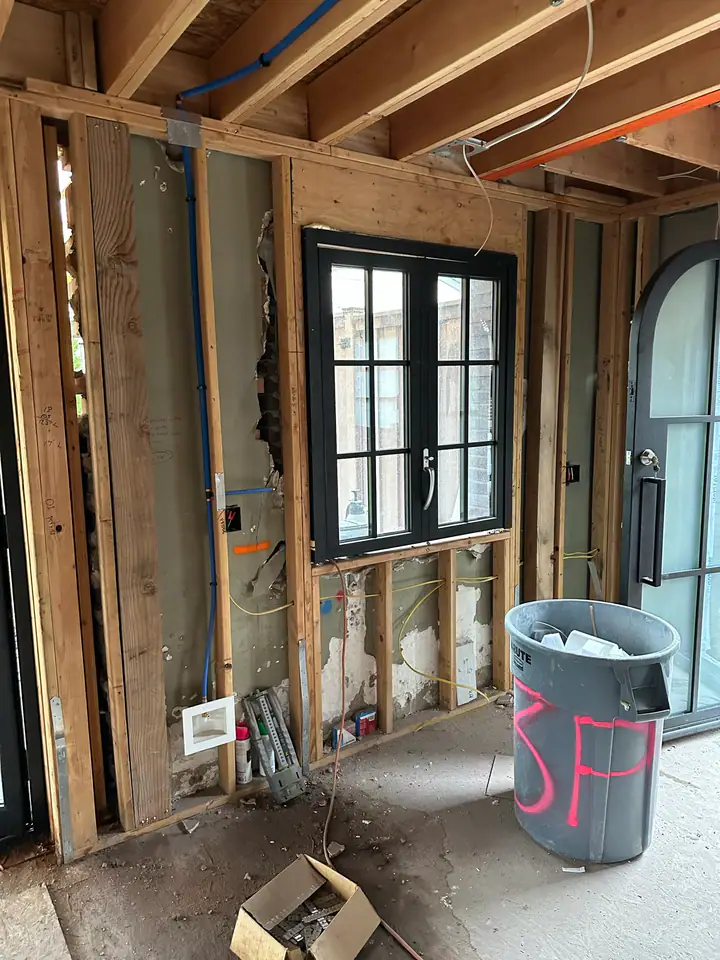 New interior framing with black-frame windows installed, natural light flooding the rebuilt space