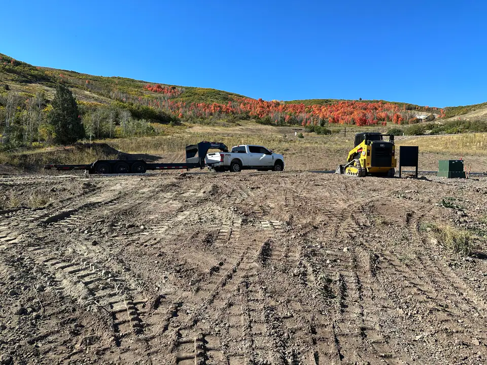 Raw mountain building lot with scrub oak, dirt, and construction equipment — Day 1 of the Park City Parade Home project