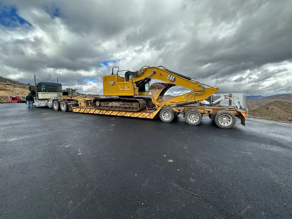 Heavy equipment arriving on flatbed trailer — Day One on the Hideout job site