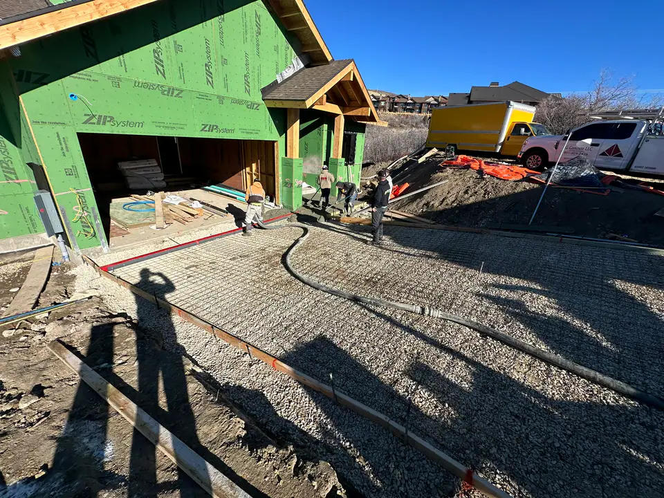 Concrete being poured for the driveway and garage pad with ZIP system garage framing visible