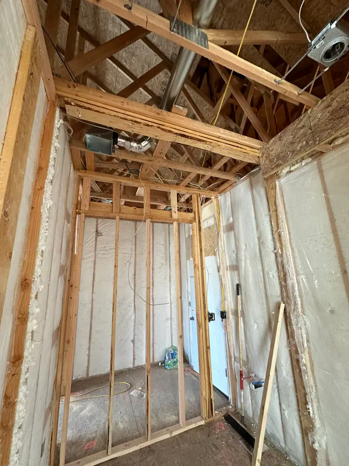 Interior framing with spray foam insulation applied to walls and ceiling, HVAC ductwork and electrical rough-in visible