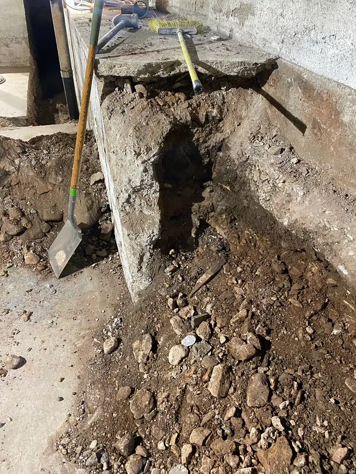 Undermined foundation footing with exposed soil beneath — structural failure in progress
