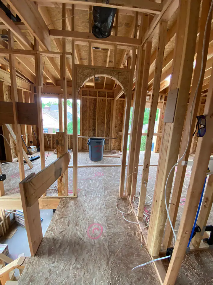 Interior framing with PEX plumbing rough-in visible — red and blue supply lines running through studs, ABS drain pipe, electrical boxes mounted