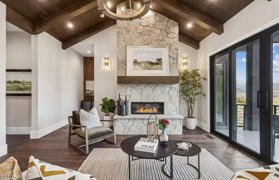 Living room with stone fireplace and floor-to-ceiling mountain views