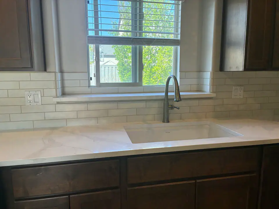 Quartz countertop with undermount sink, subway tile backsplash, and brushed nickel faucet — finished kitchen detail